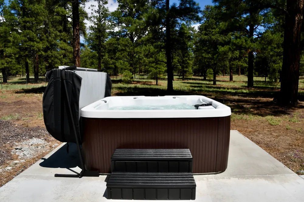 The six-person hot tub on its concrete pad among the pines