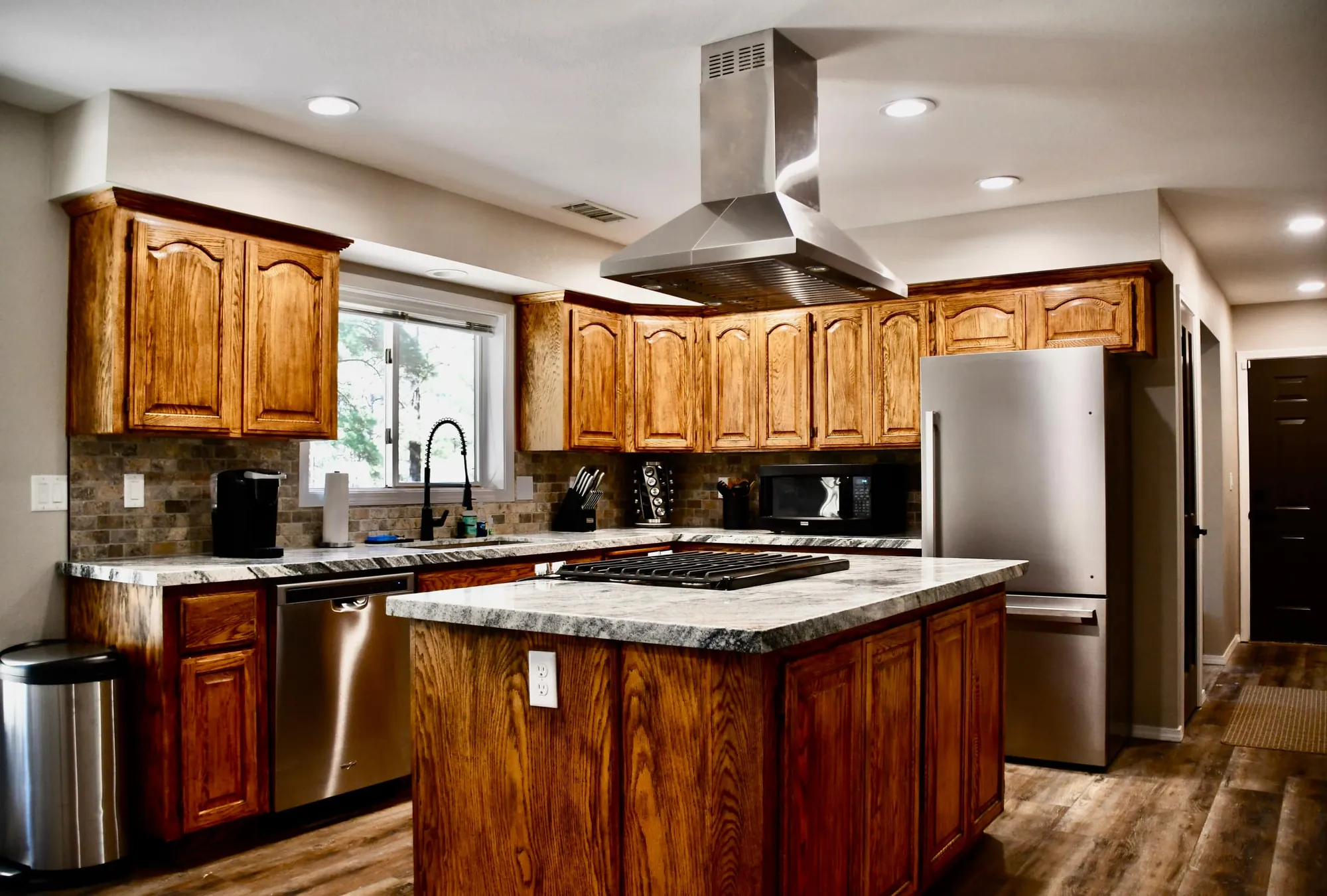 Kitchen with oak cabinets, a granite island, gas range and stainless appliances